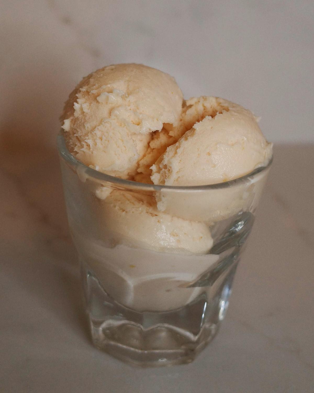 3 scoops of blood orange ice cream in a clear glass.