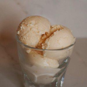 three scoops of blood orange ice cream in a clear glass.