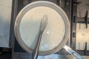 milk and cream ice cream base in a saucepan with a whisk.