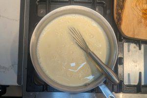 ice cream custard base in a saucepan with a whisk.