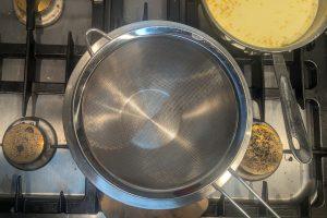 a fine mesh sieve set over a stainless steel bowl.