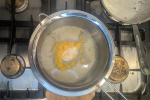 blood orange custard strained through a fine mesh sieve into a stainless steel bowl.