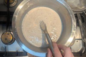 stirring blood orange juice into cooled blood orange custard with a whisk.