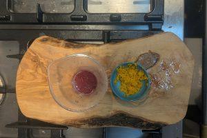 blood orange juice in a small plastic container next to a small blue bowl with blood orange zest.