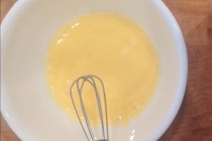 tempered egg yolk in a bowl with a mini whisk.