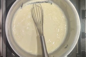 custard ice cream base in a saucepan with a whisk.