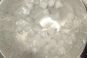 a large stainless bowl filled with water and ice cubes.