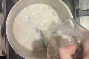 pouring milk into a saucepan with sugar, guar gum, and skim milk powder.