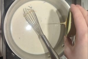 pouring honey into ice cream base in a saucepan.