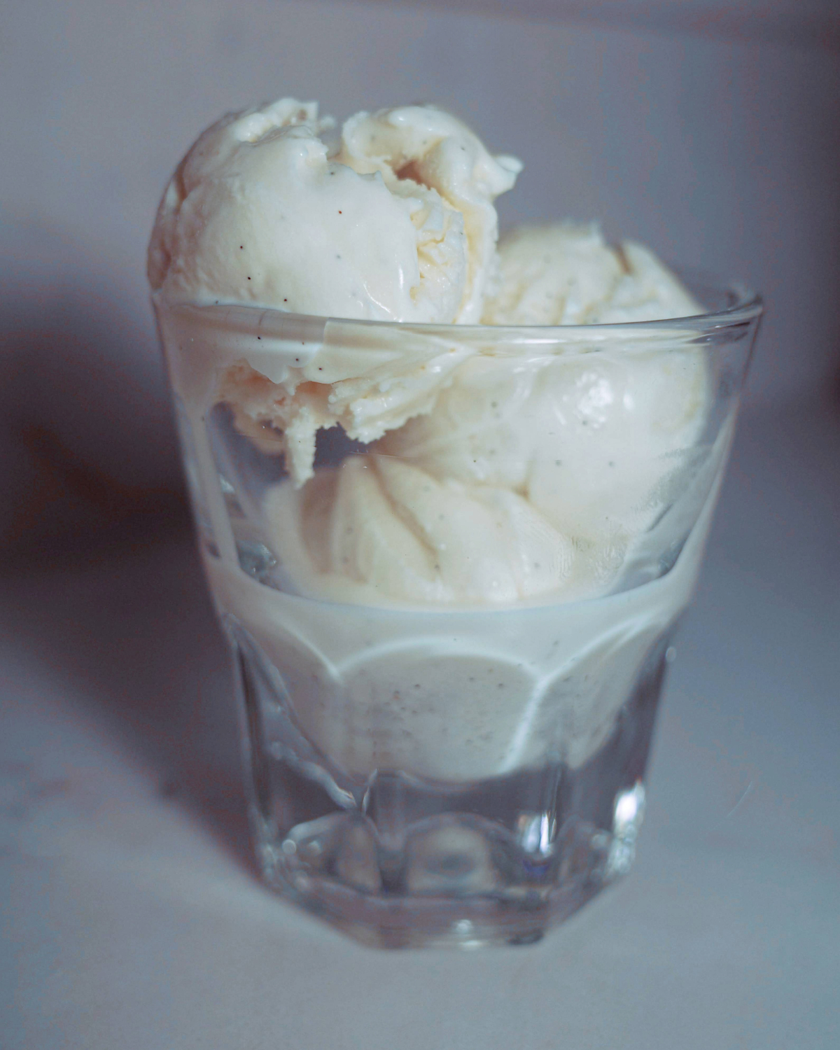 three scoops of vanilla bean honey ice cream in a clear glass.