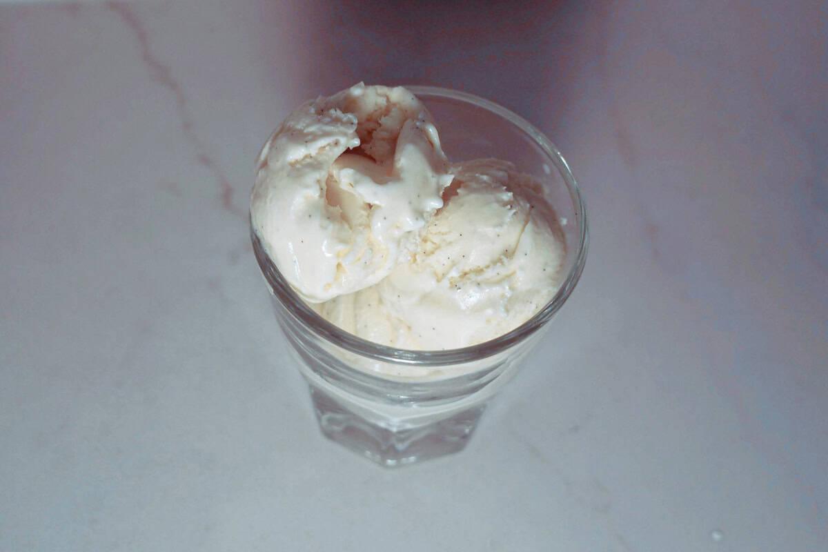 three-quarters view of scoops of vanilla bean honey ice cream in a clear glass.