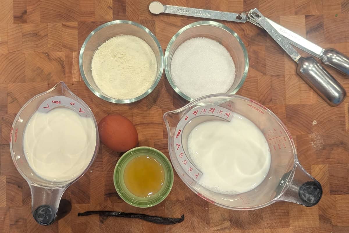 measured ingredients for vanilla bean honey ice cream on a butcher block.