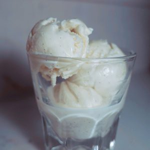 three scoops of vanilla bean honey ice cream in a clear glass.