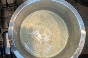 pistachio paste blended into ice cream base in a stainless bowl.