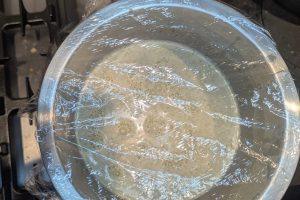 freshly made pistachio ice cream base in a stainless bowl topped with plastic wrap.
