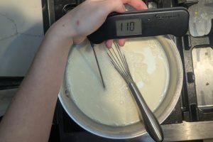 a thermometer reads 110°F dipped into ice cream base in a saucepan.