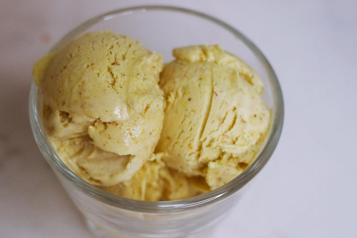 overhead closeup view of three scoops of pistachio ice cream in a glass.