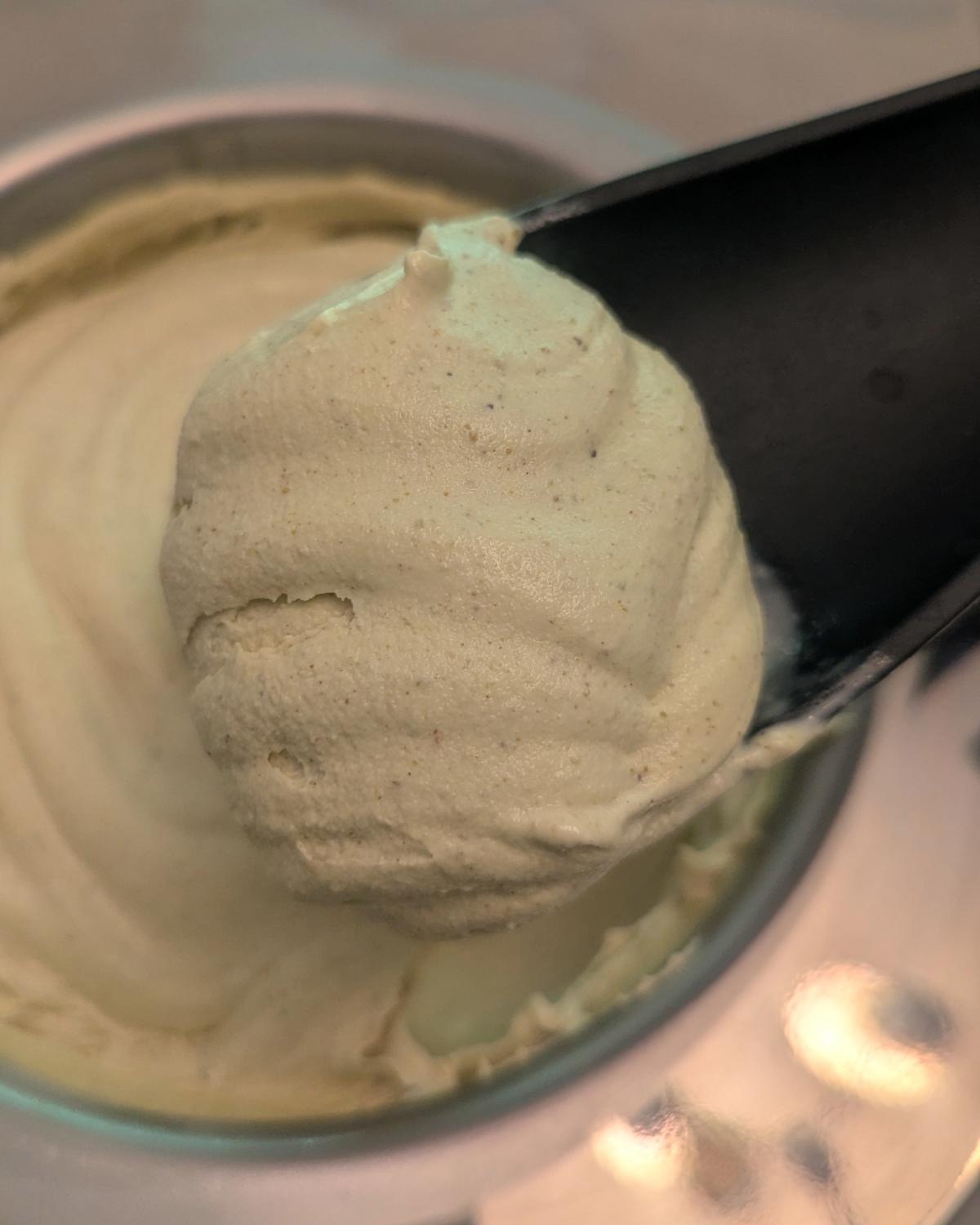 closeup of freshly churned pistachio ice cream on a spoonula showing the ideal texture for this ice cream base ratio.