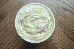 overhead view of a freshly packed pint of pistachio ice cream with rhubarb jam swirl.