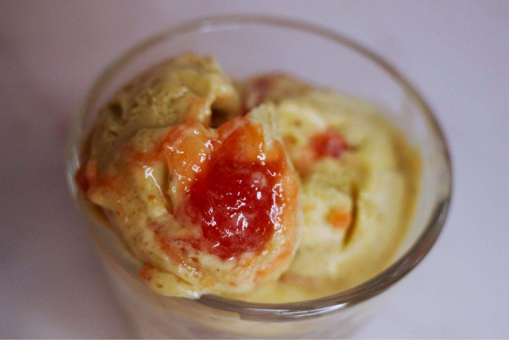 three scoops of pistachio ice cream with rhubarb jam in a glass.