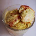 three-quarters view of three scoops of pistachio ice cream with rhubarb jam in a glass.