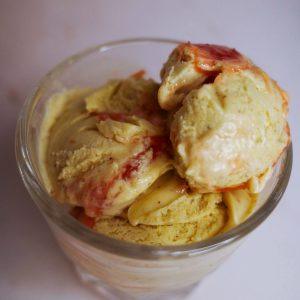 three-quarters view of three scoops of pistachio ice cream with rhubarb jam in a glass.
