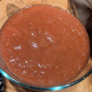 thick pink homemade rhubarb jam in a glass container.