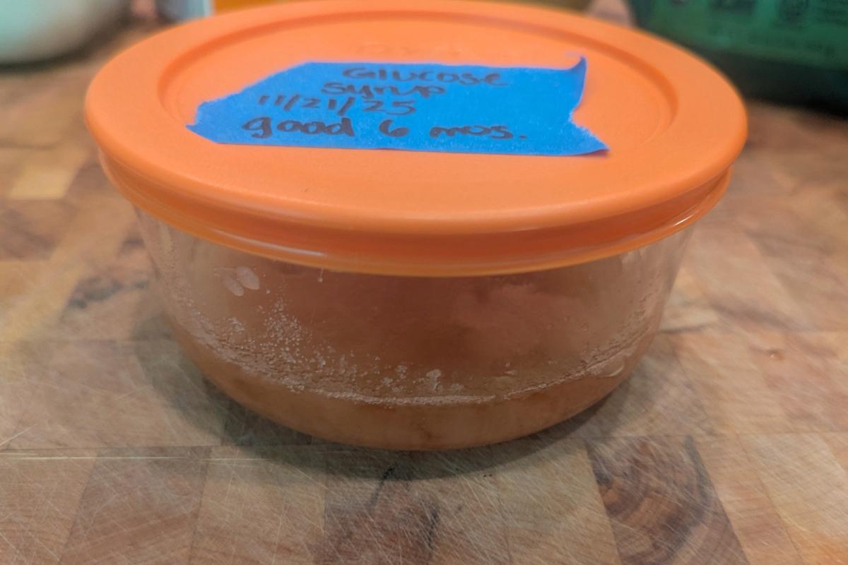 side view of glucose syrup in a glass container with an orange top.