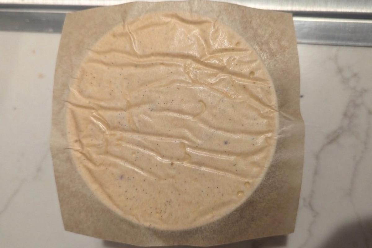 overhead view of a pint of ice cream with a square of brown wax paper pressed to the surface.