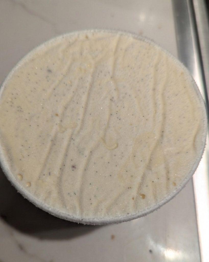 closeup of a pint of vanilla ice cream with a fine layer of ice crystals on top.