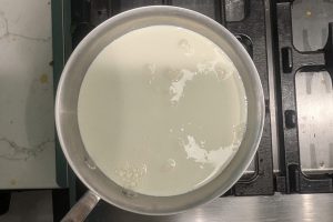 whole milk and heavy cream poured over sugar and skim milk powder in a saucepan.