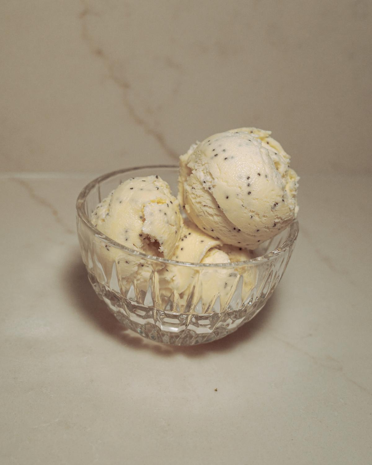 three scoops of lemon poppy seed ice cream in a glass dish.