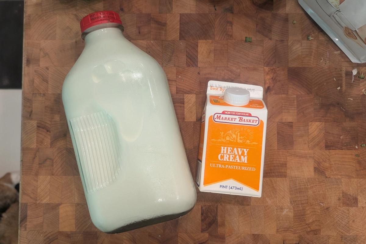 overhead view of a glass gallon of milk next to a carton of Market Basket heavy cream.