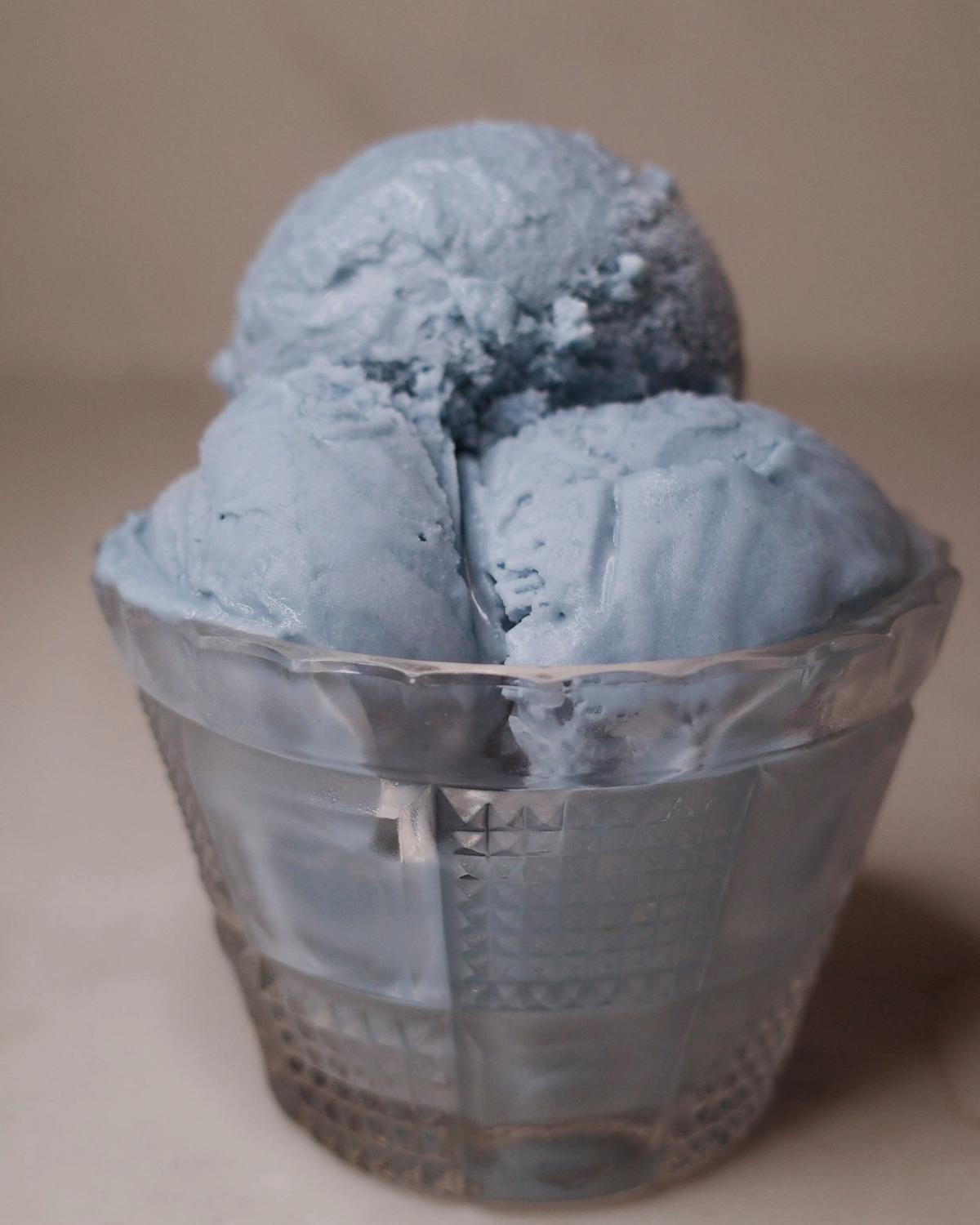 three scoops of blue vanilla ice cream in a glass bowl.