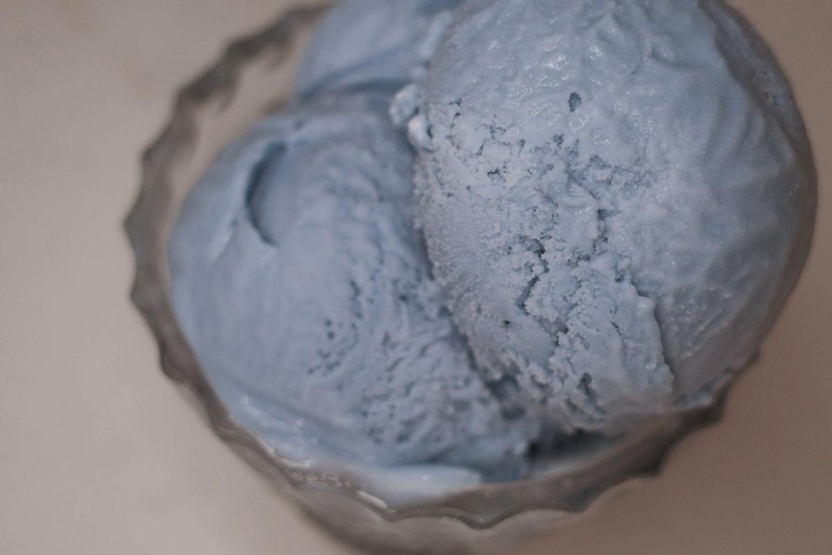 closeup overhead view of blue vanilla ice cream in a glass dish.