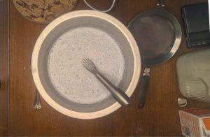 blue vanilla ice cream base in a metal bowl with a whisk.