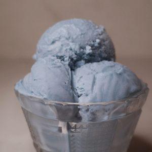 three scoops of blue vanilla ice cream in a glass bowl.