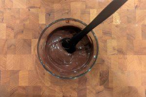 melted chocolate in a glass bowl with a rubber spatula.