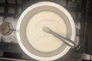 vanilla extract, coffee liqueur, and salt added to coffee custard in a stainless bowl.