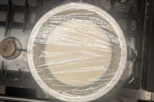 coffee liqueur custard covered with plastic wrap in a stainless bowl.