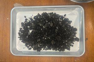 crushed oreo cookies mixed with butter into crumbles on a tray.