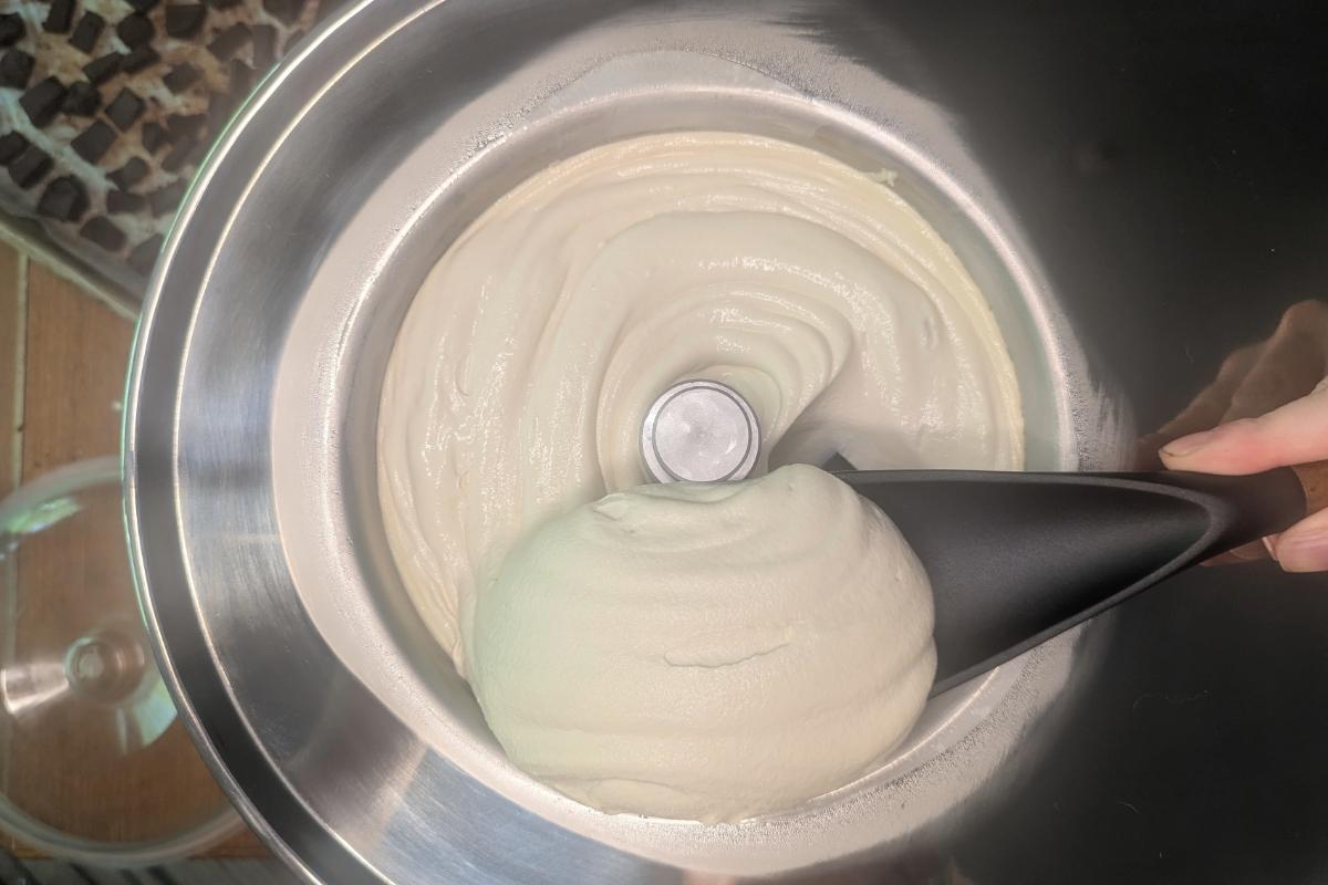 lifting a scoop of freshly churned coffee liqueur ice cream from an ice cream maker.