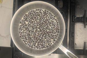 milk and coffee beans in a saucepan after steeping.