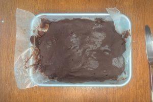chocolate ganache fudge chunks mixture spread out on a lined baking sheet.