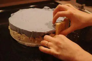 placing vanilla cream wafer cookies around the sides of an ice cream cake.