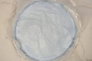 blue vanilla ice cream topped with wax paper in a springform pan.