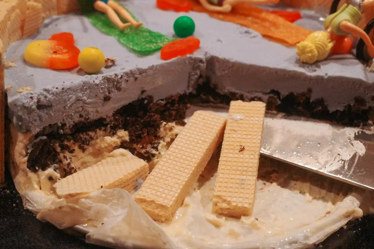 the aftermath of a partially eaten swimming pool cake with wafers strewn about.