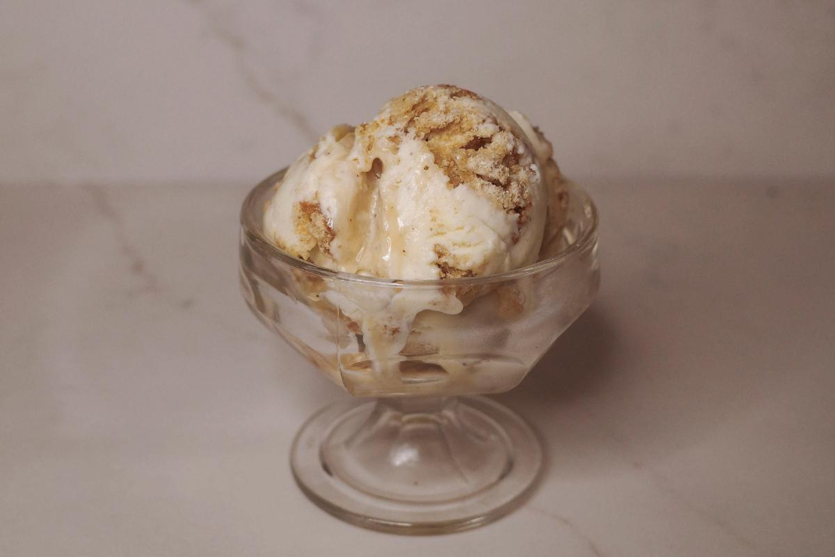 scoops of caramel cider donut ice cream swirled with apple cider caramel sauce in a dish.