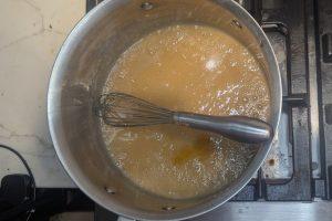 vanilla added to apple cider caramel in a saucepan with a whisk.