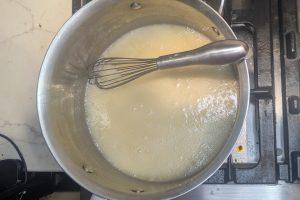 cream added to caramel in a saucepan with a whisk.